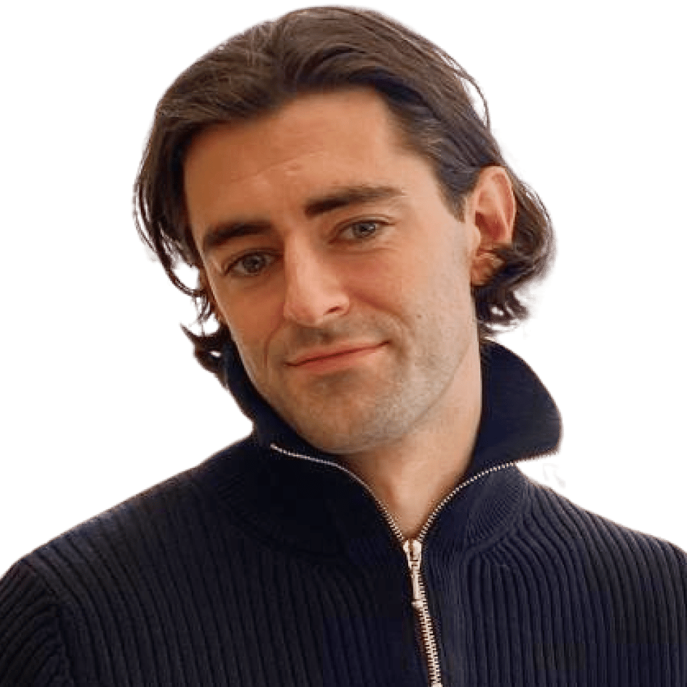 Speaker profile headshot of a man with shoulder-length brown hair wearing a navy ribbed sweater.