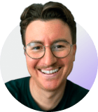 Profile headshot of a smiling person with glasses wearing a dark shirt, against a gradient white-to-purple background.